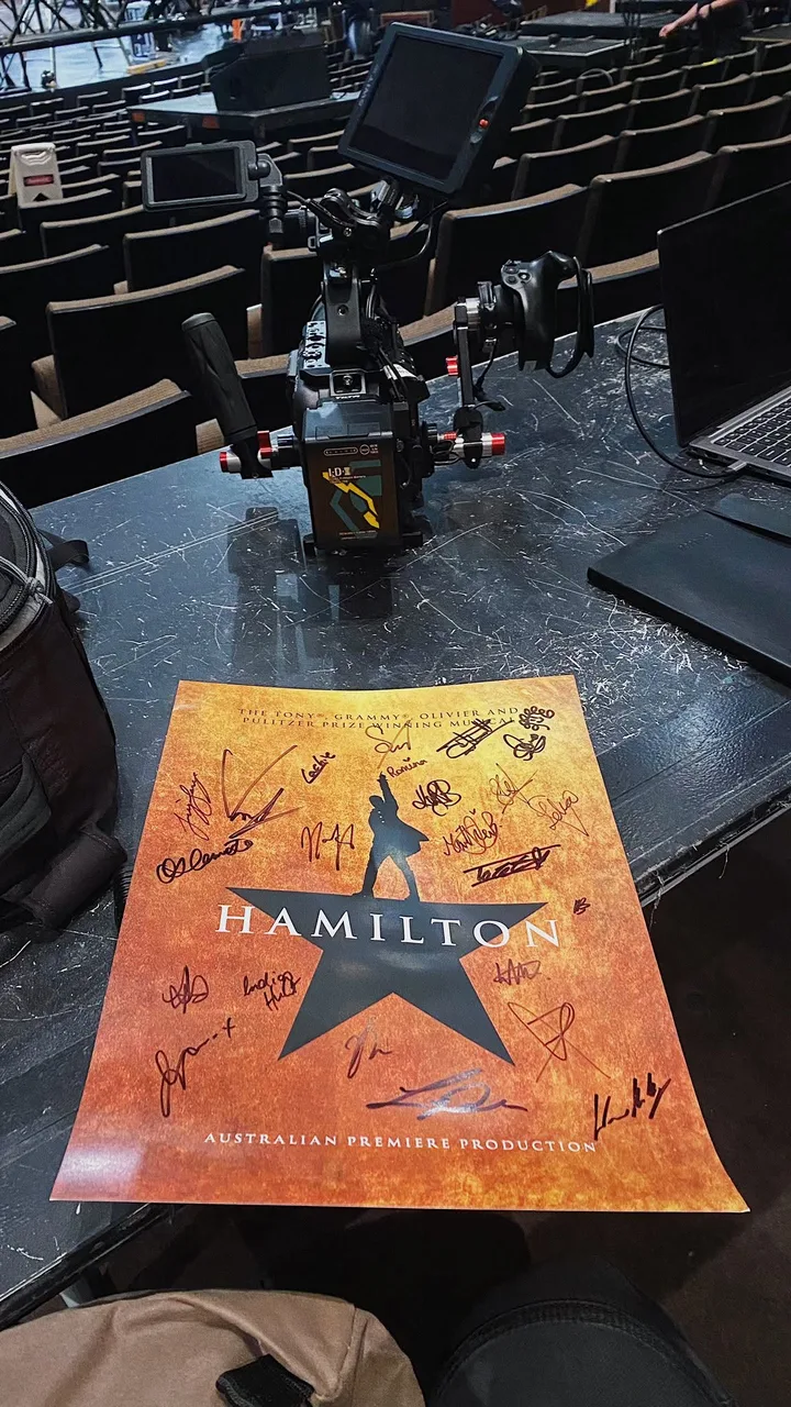 A signed Hamilton Australia playbill beside production camera equipment in a QPAC auditorium