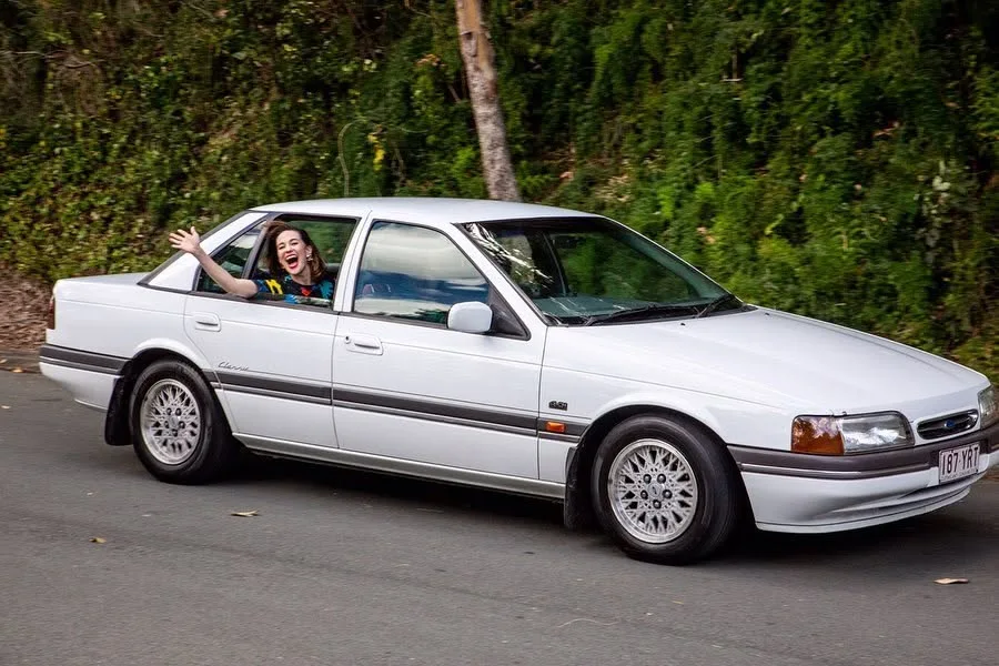 Stefanie Jones waving from the car during the Goodbye Porpoise Spit recreation in Coolangatta